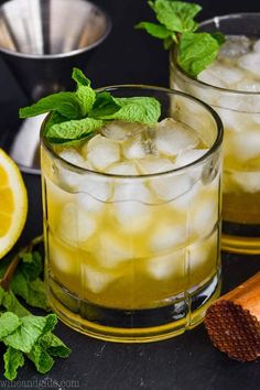 two glasses filled with ice and mint on top of a table