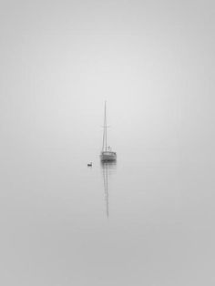 a boat floating on top of a body of water in the middle of a foggy day