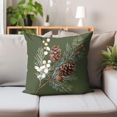 a green pillow sitting on top of a white couch next to a potted plant