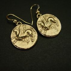 "Handmade Pegasus earrings perfect gift for Percy Jackson fans. This coin represents Pegasus the winged divine stallion usually depicted as pure white in colour. He was sired by Poseidon, in his role as horse-god, and foaled by the Gorgon Medusa. Greco-Roman poets write about his ascent to heaven after his birth and his obeisance to Zeus, king of the gods, who instructed him to bring lightning and thunder from Olympus. - Handmade reproduction of an ancient Greek coin from 250 BC. - Solid yellow bronze also called jeweler gold bronze coins - The coins are 5/8\" wide. - One-sided hammered coin - 14K gold filled ear wire.  - Gold filled has 100 times more gold than plated thus does not rub or peel off.  - Nickel free. - Each piece is fired individually thus sizes and colors may vary slightly Handmade Medallion Earrings As Gift, Handmade Medallion Earrings For Gift, Nickel-free Medallion Earrings For Gift, Nickel Free Medallion Earrings Gift, Symbolic Round Earrings For Pierced Ears, Nickel-free Coin Shaped Earrings For Gifts, Nickel Free Coin Shaped Earrings For Gift, Brass Medallion Earrings As A Gift, Lightning And Thunder