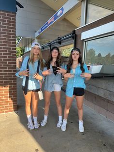 three girls are standing in front of a building and posing for the camera with their hands together