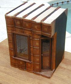 an old book like building made out of books on a wooden table next to a swimming pool