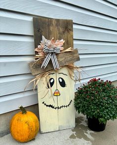 a wooden box with a face painted on it next to a potted planter