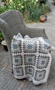 a crocheted blanket sitting on top of a chair next to a potted plant