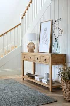 a wooden table with two vases on top of it next to a stair case