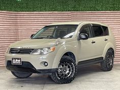 a white suv parked in front of a brick wall