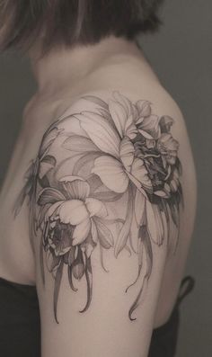 a woman's shoulder with flowers and leaves on her arm, in black and white