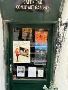 a green door that has some books on it in front of a building with plants