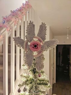 a crocheted owl decoration on top of a christmas tree in a house with stairs