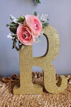 the letter b is decorated with flowers and greenery