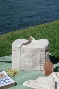 a bottle of wine sitting on top of a blanket next to a book and bag