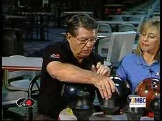 an older man and woman sitting at a table working on something in front of them