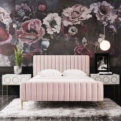 a bed with pink velvet upholstered headboard and foot board in front of a floral wallpaper