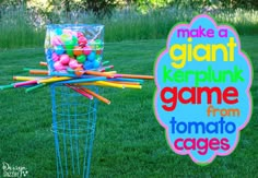 there is a basket full of colored balls in the grass with a sign that says make a giant kerppunk game from tomato cages