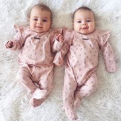 two baby babies laying on top of a white blanket