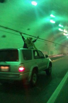 a car driving through a tunnel with two people on the roof and one person in the back