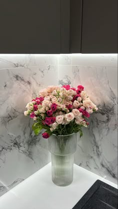 a vase filled with pink and white flowers on top of a counter