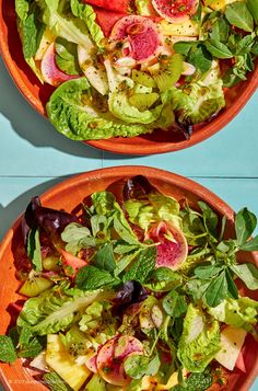 two orange bowls filled with salad on top of a blue table