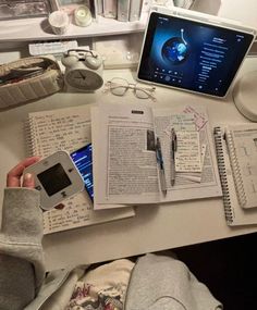 an open book sitting on top of a desk next to a laptop computer and cell phone