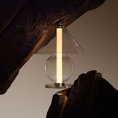 a lamp that is sitting on top of a rock next to a large piece of wood