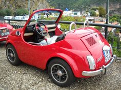 an old style red car parked on the side of a road