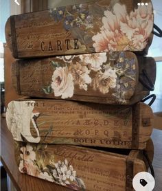 three wooden boxes are stacked on top of each other, with floral designs and words painted on them