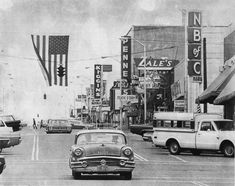 an old black and white photo of cars driving down the street