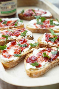 several pieces of bread with cheese and toppings on them sitting on a tray next to a bottle of ketchup