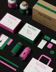 an assortment of packaging and accessories on a black surface with pink, green, and white colors