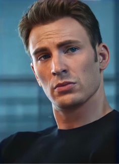 a close up of a person wearing a black shirt and looking at the camera with a serious look on his face