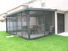 an enclosed patio with chairs and table in the grass