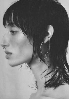 a black and white photo of a woman's face with earrings on her ear