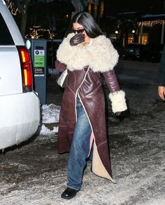 a woman in a leather coat is walking down the street