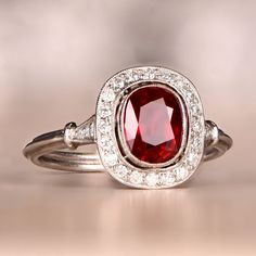 a close up of a ring with a red stone in the middle and white diamonds around it