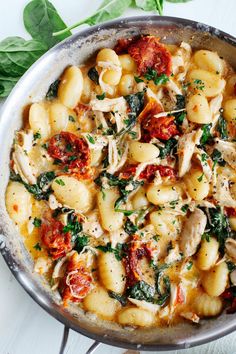 a pan filled with pasta and spinach on top of a table