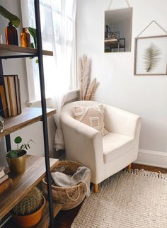 a living room with a white chair and bookshelf filled with plants on top of it