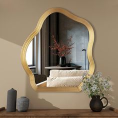 a mirror sitting on top of a dresser next to a vase