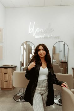 a woman standing in front of a hair salon with her arms on the back of a chair