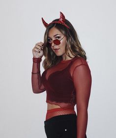 a woman with red makeup and devil horns on her head is posing for the camera