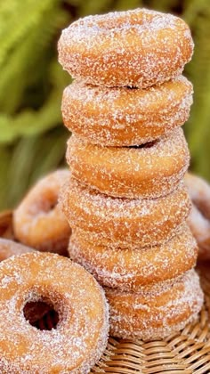 a stack of sugar covered donuts sitting on top of a basket next to some plants