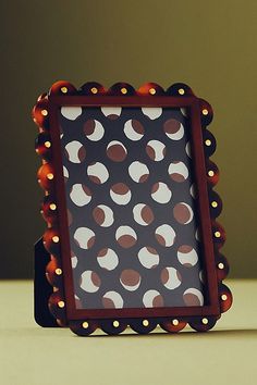 a small photo frame sitting on top of a white table next to a red and black object