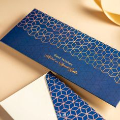 a blue and gold business card sitting on top of a white table next to a plate