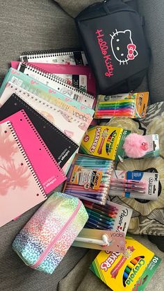 many school supplies are laid out on the couch next to a book and pencils