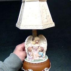 a lamp with an angel figurine sitting on it's base next to a hand