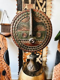 a wooden mask is sitting on top of a vase next to other decorative items and wall hangings