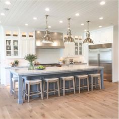 a large kitchen with an island in the middle and four stools at the end