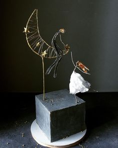 a sculpture made out of metal and wire on top of a block of concrete with gold stars