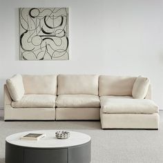 a living room with a white couch and coffee table in front of a painting on the wall