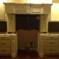 an unfinished kitchen with white cabinets and wood floors in the process of remodeling