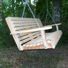 a wooden swing hanging from a tree in the woods